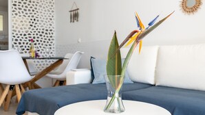 A modern living room with a white sofa, a round white table, and a glass vase with a bird of paradise flower.