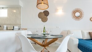 A modern dining area with a round glass table, white chairs, and a wooden floor.