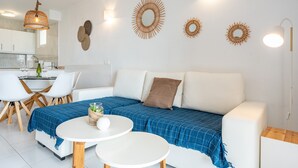 A modern living room with a sofa, two round tables, and wall decor.