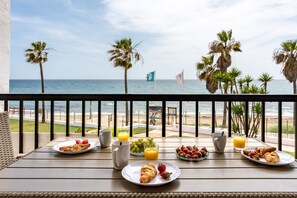 A balcony with breakfast items, a view of the beach, and palm trees. - Beach Front house - Full Sea view - Dona Lola Beach Resort - Marbella - Mijas (Marbella)