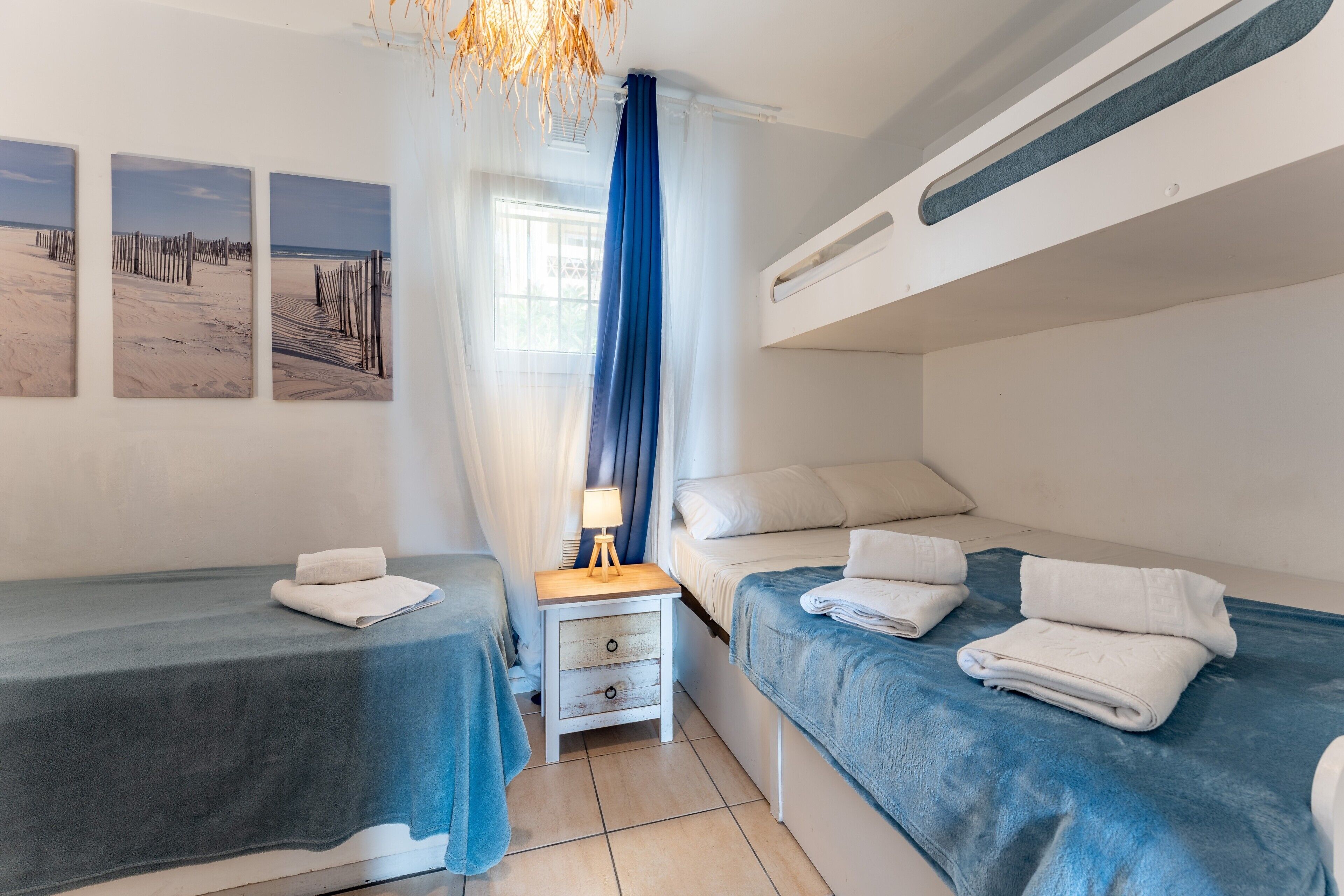 Un dormitorio con dos camas, una mesita de noche y una ventana con cortinas.