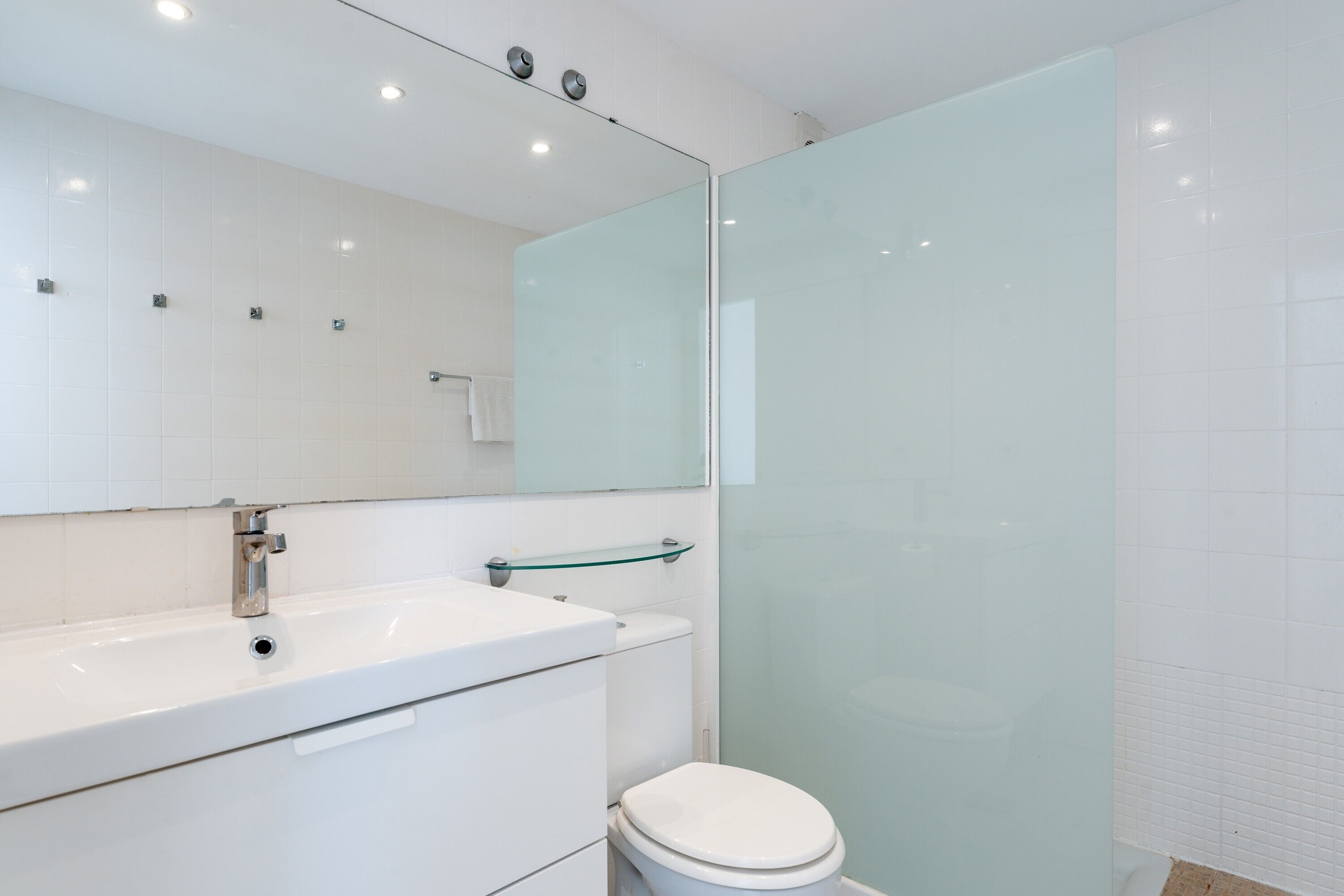 A modern bathroom with a glass shower enclosure, a white sink, and a toilet.