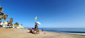 A beach with palm trees, a lifeguard tower, and umbrellas.
