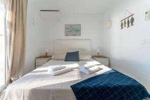 Una cama bien hecha con toallas dobladas, una colcha azul y una obra de arte en la pared.