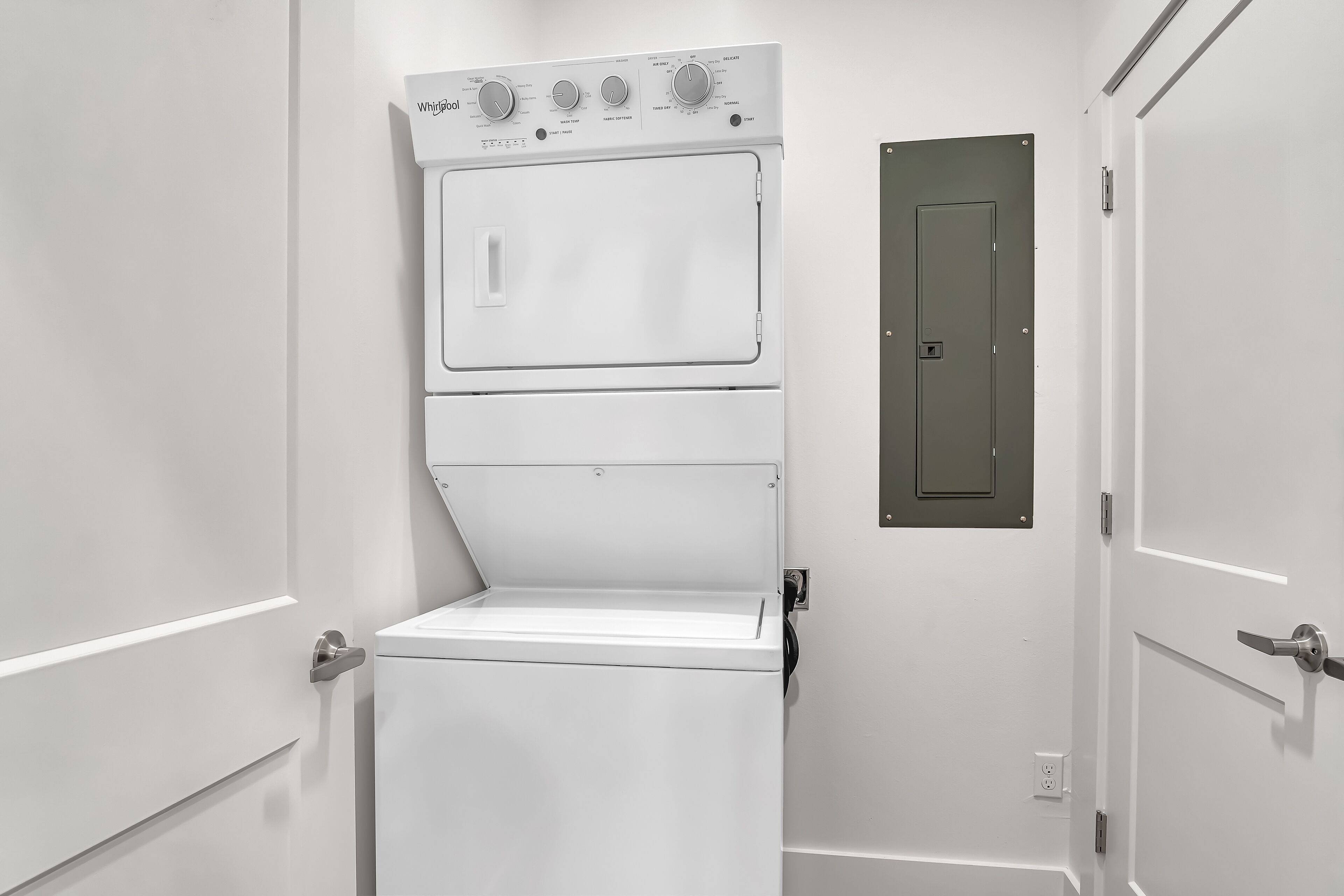 A white, wall-mounted washer and dryer unit with control knobs and a door.