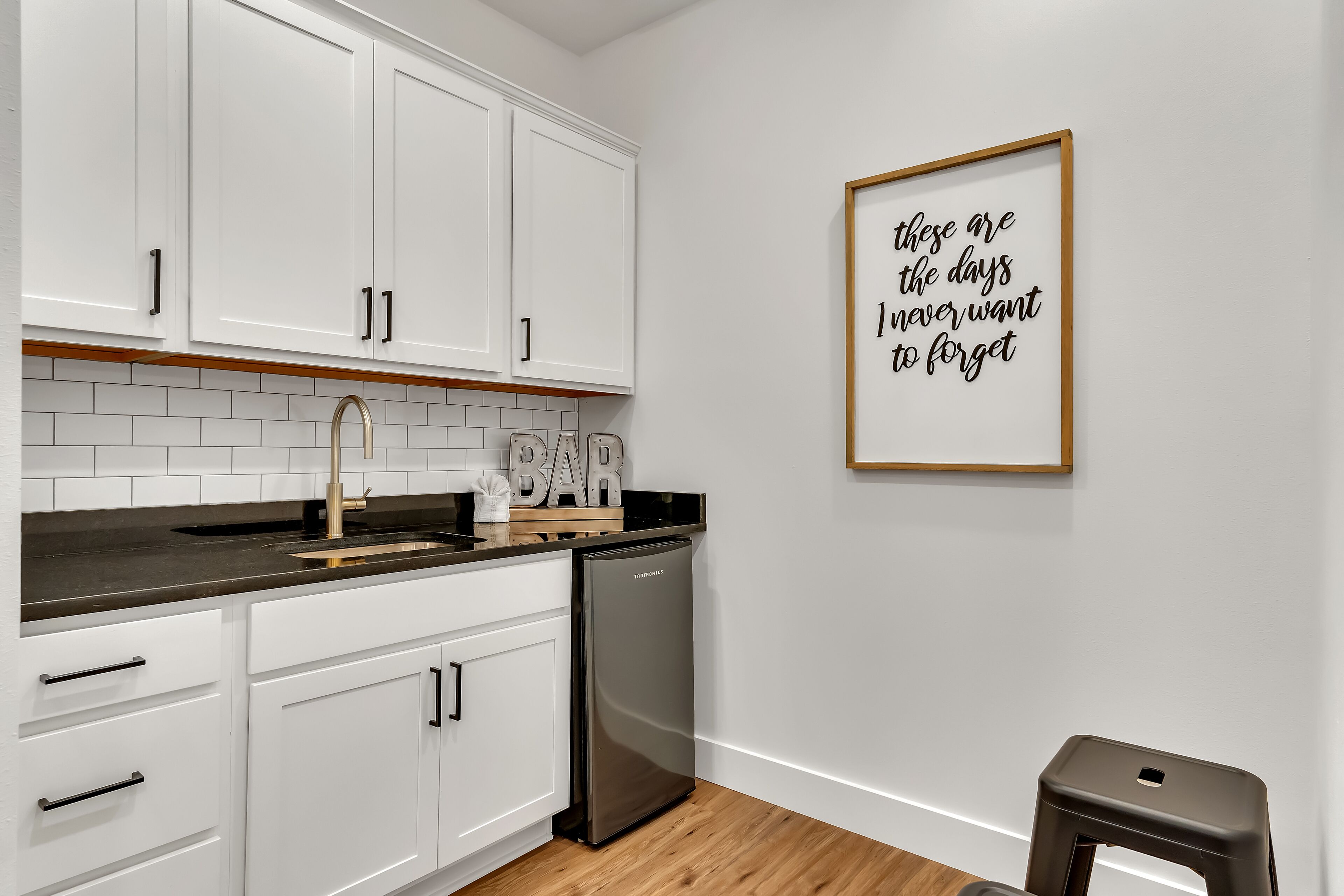 A modern kitchen with white cabinets, a stainless steel refrigerator, and a wooden countertop.