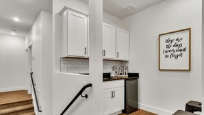 Una cocina moderna con armarios blancos, lavavajillas y una encimera con un letrero que dice 'BAR'.