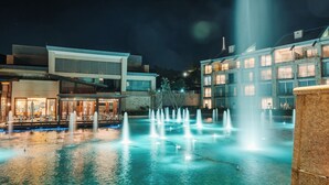 A nighttime view of a hotel with a pool area featuring multiple fountains. - Silverstar Hotel  (Krugersdorp)