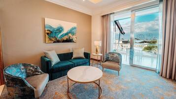 A hotel room with a teal sofa, two armchairs, a round coffee table, and a large abstract painting on the wall.