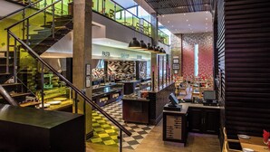 A modern restaurant with a checkered floor, a staircase, and a bar area. - Silverstar Hotel  (Krugersdorp)