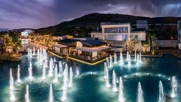 A waterfront hotel with multiple dining areas, a pool with fountains, and a mountain backdrop. - Silverstar Hotel  (Krugersdorp)