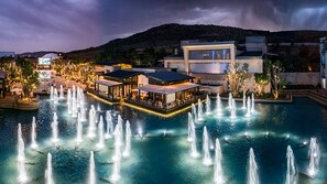 A waterfront hotel with multiple dining areas, a pool with fountains, and a mountain backdrop. - Silverstar Hotel  (Krugersdorp)
