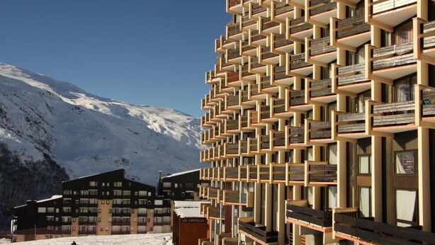 Un edificio moderno con una facciata geometrica unica, situato in una zona montuosa innevata.