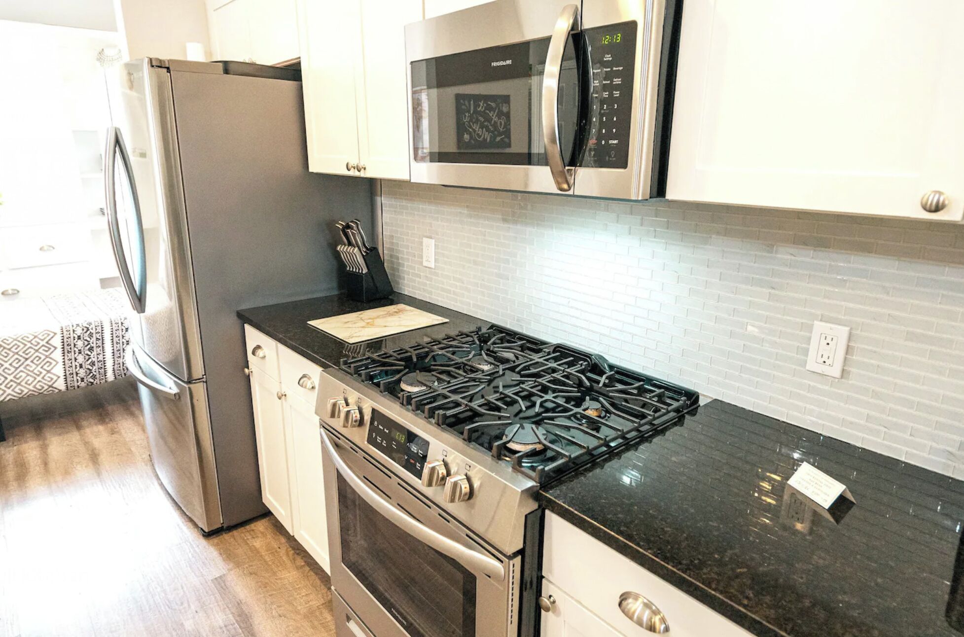 Una cocina equipada con estufa, horno, microondas y refrigerador de acero inoxidable.