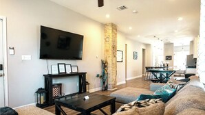 Un salón amplio con una gran televisión de pantalla plana, chimenea y un pilar de piedra.