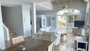 A spacious living area with a wooden dining table, a sofa, and a TV. - Villa Morning Glory - Private Pool - Amazing Views (St Thomas)