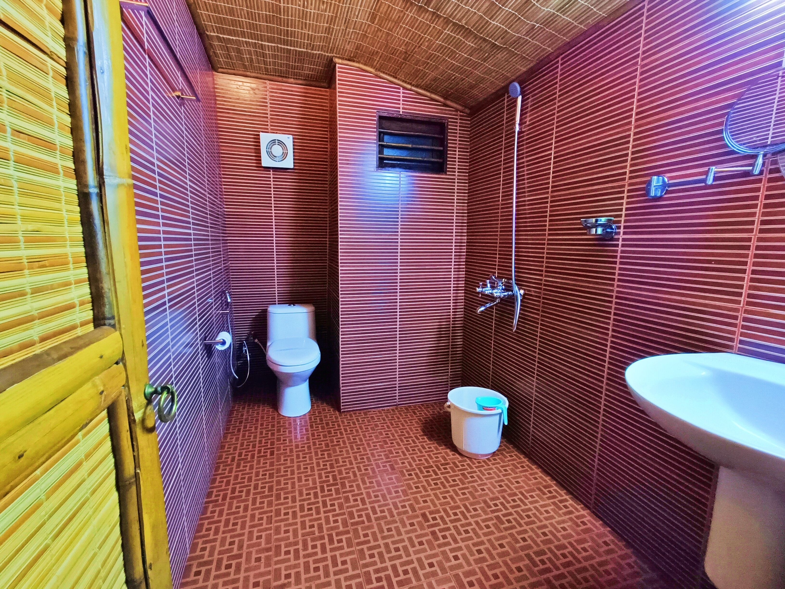 A bathroom with a toilet, shower, and sink.