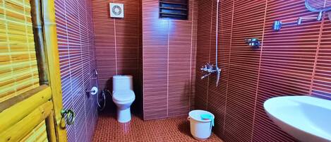 A bathroom with a toilet, shower, and sink.