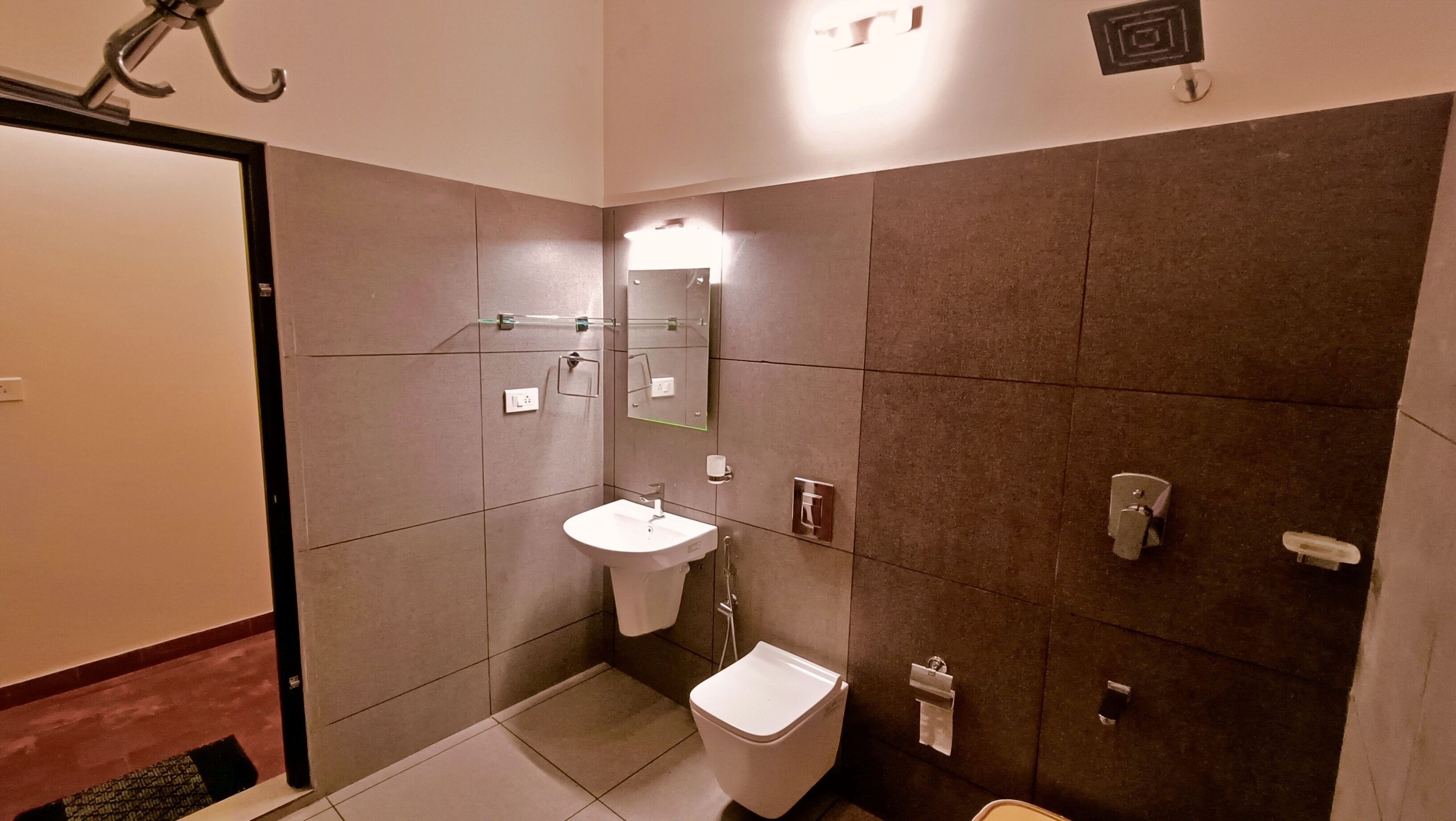 A modern bathroom with a sink, toilet, and hand dryer.
