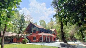 Un immeuble de deux étages avec une façade en briques rouges, un balcon et un escalier menant à l’étage supérieur.