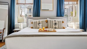 Una habitación de hotel con cama, bandeja de desayuno, espejo y ventana con cortinas.