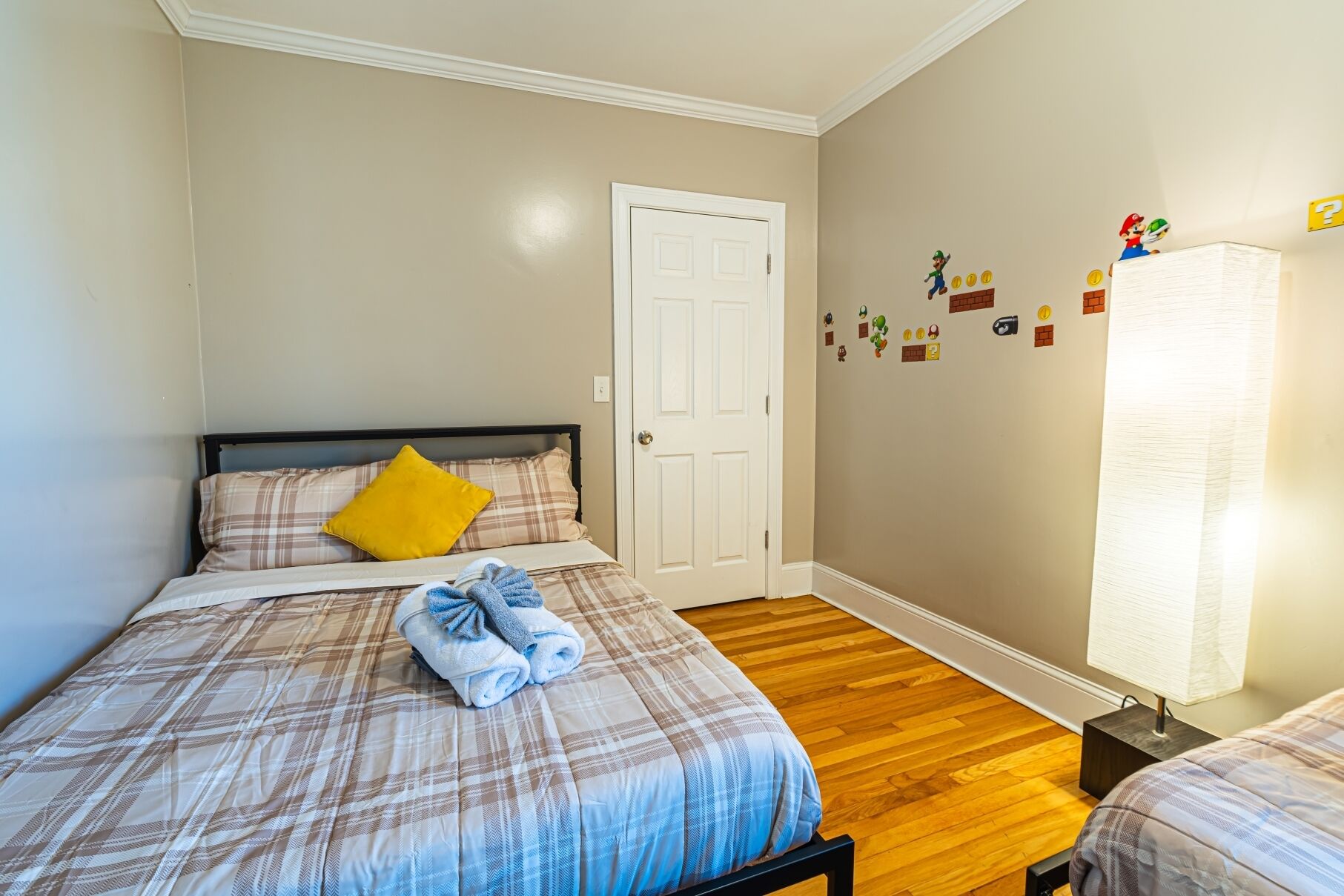 A bedroom with a bed, a nightstand, a door, and wall decorations.