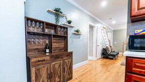 Un meuble en bois contenant des verres à vin et une bouteille, un escalier et un téléviseur.