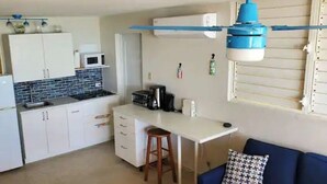 A compact kitchen with white cabinets, a microwave, and a small dining area with a blue sofa.