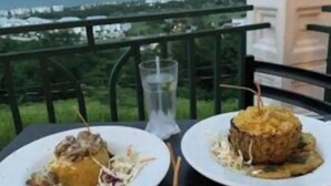 A table with various dishes, a glass of water, and a view of the ocean.