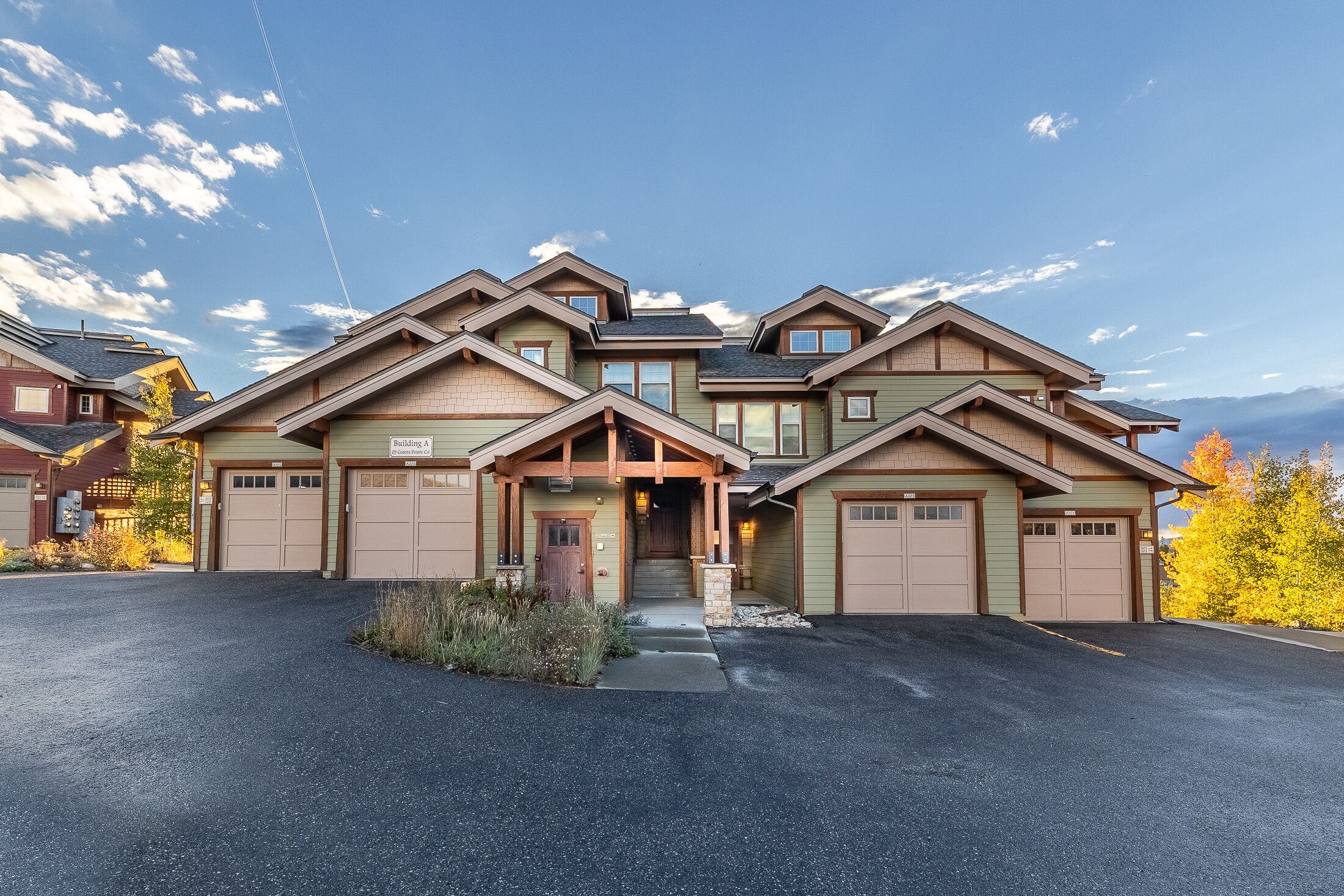 A multi-story building with a garage entrance, a covered porch, and a driveway leading to the entrance.