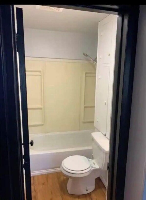 Een badkamer met toilet, bad en douche.