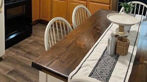 A kitchen with dark cabinets, a wooden table, and a stove. - Main St., Sturgis Rally Rental!! Enough Said!! (Sturgis)