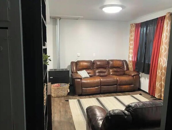 A living room with a brown leather sofa, a small side table, a woven basket, and a striped rug.