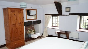 Un dormitorio con una cama grande, un armario de madera, un espejo, una ventana con cortinas y un radiador.