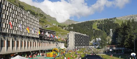 A hotel with multiple floors, outdoor seating, and a view of mountains.