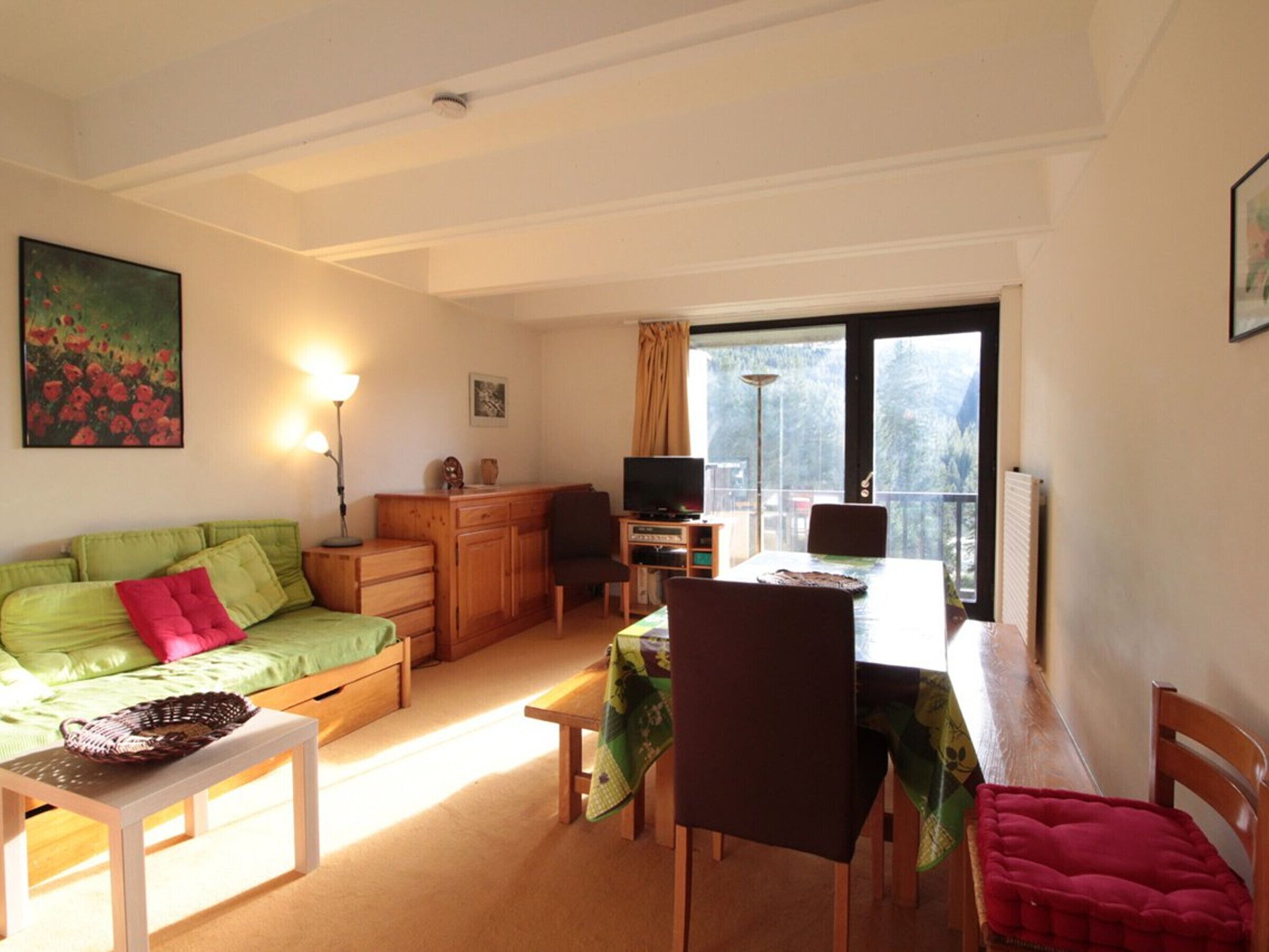 Una sala de estar acogedora con un sofá verde, una mesa de centro de madera y un comedor con una mesa y sillas.