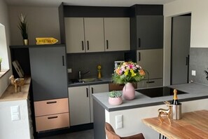 Eine moderne Küche mit grauen Schränken, einer Holzarbeitsplatte und einer kleinen Essecke mit Tisch und Stühlen.