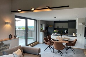 Eine moderne Küche mit Essbereich, großen Fenstern und Blick ins Freie.