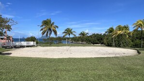 A beach area with a volleyball net, palm trees, and a view of the ocean. - Studio Ti Paradise Magnifique vue mer et Diamant (Sainte-Luce)