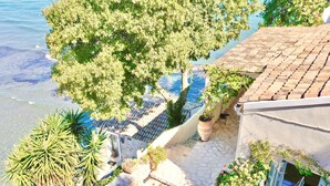 Un edificio costiero con facciata in pietra, tetto in tegole e un balcone che si affaccia sul mare.