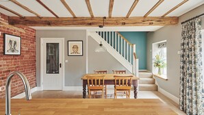 Ein Essbereich mit Holztisch und Stühlen, einer Treppe und Blick ins Freie.