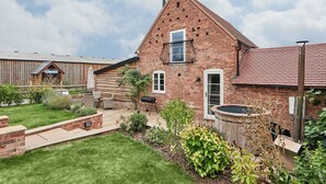 Ein Ziegelhaus mit Balkon, Holzzaun und einem Garten mit verschiedenen Pflanzen.