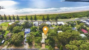 An aerial view of a coastal area with houses, a road, and a beach.