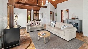 A spacious living room with a fireplace, two sofas, a coffee table, and a rustic wooden ceiling.