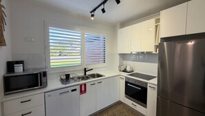 Een moderne keuken met witte kasten, roestvrijstalen apparatuur, een magnetron, een spoelbak en een vaatwasser.