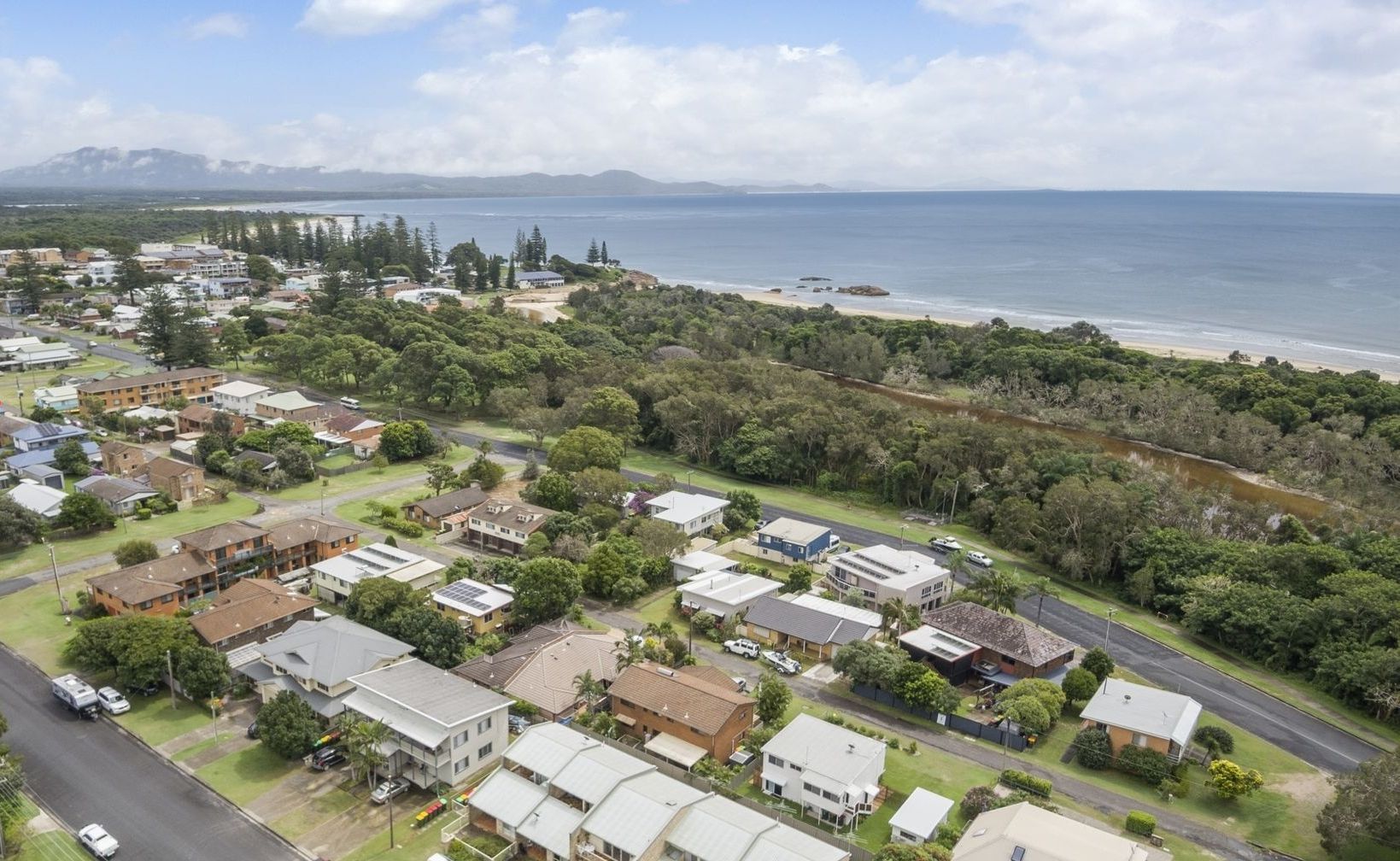 Vista aérea de una zona residencial con casas, calles y una costa.