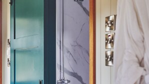 A bathroom with a blue door, a shower, and a white robe hanging on the wall. - The Hangout Hut - Luxury Cottages (Worcester)