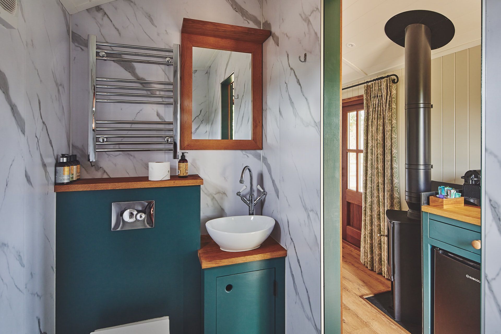 Une salle de bain avec un mur en marbre, un lavabo, un miroir et un porte-serviettes.
