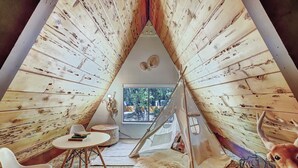 A cozy interior with a wooden tent structure, a round table, white chairs, a plush rug, and a toy train. - Scenic A-frame - Hot Tub, Basketball Court, Treehouse, Outdoor theater! (Grass Valley)