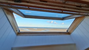 Un tragaluz en una habitación con vistas a la playa y al océano.